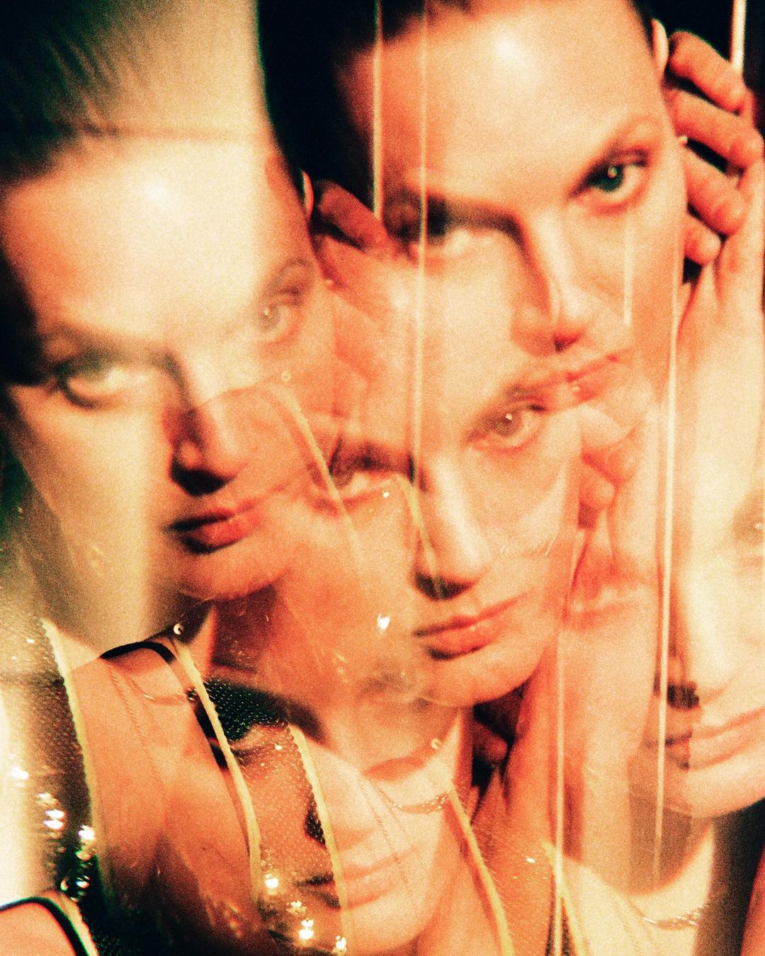 Close-up portrait of two fair-skinned adult models with neutral expressions, layered with transparent effects and a blurred focus.