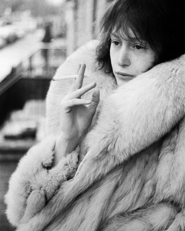 Black and white portrait of a woman in a heavy fur coat holding a cigarette, photographed by Bryan Liston.