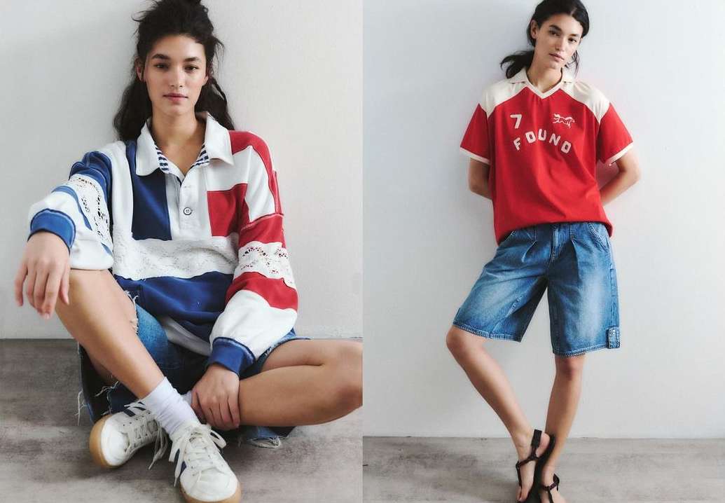 Two women pose against a white wall in colorful short denim outfits. One is sitting wearing a patchwork shirt and sneakers; the other stands in sandals.