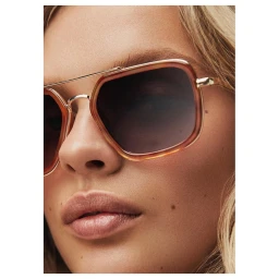 Close-up portrait of a woman wearing tortoiseshell aviator sunglasses with tinted gradient lenses and thin metal frames.