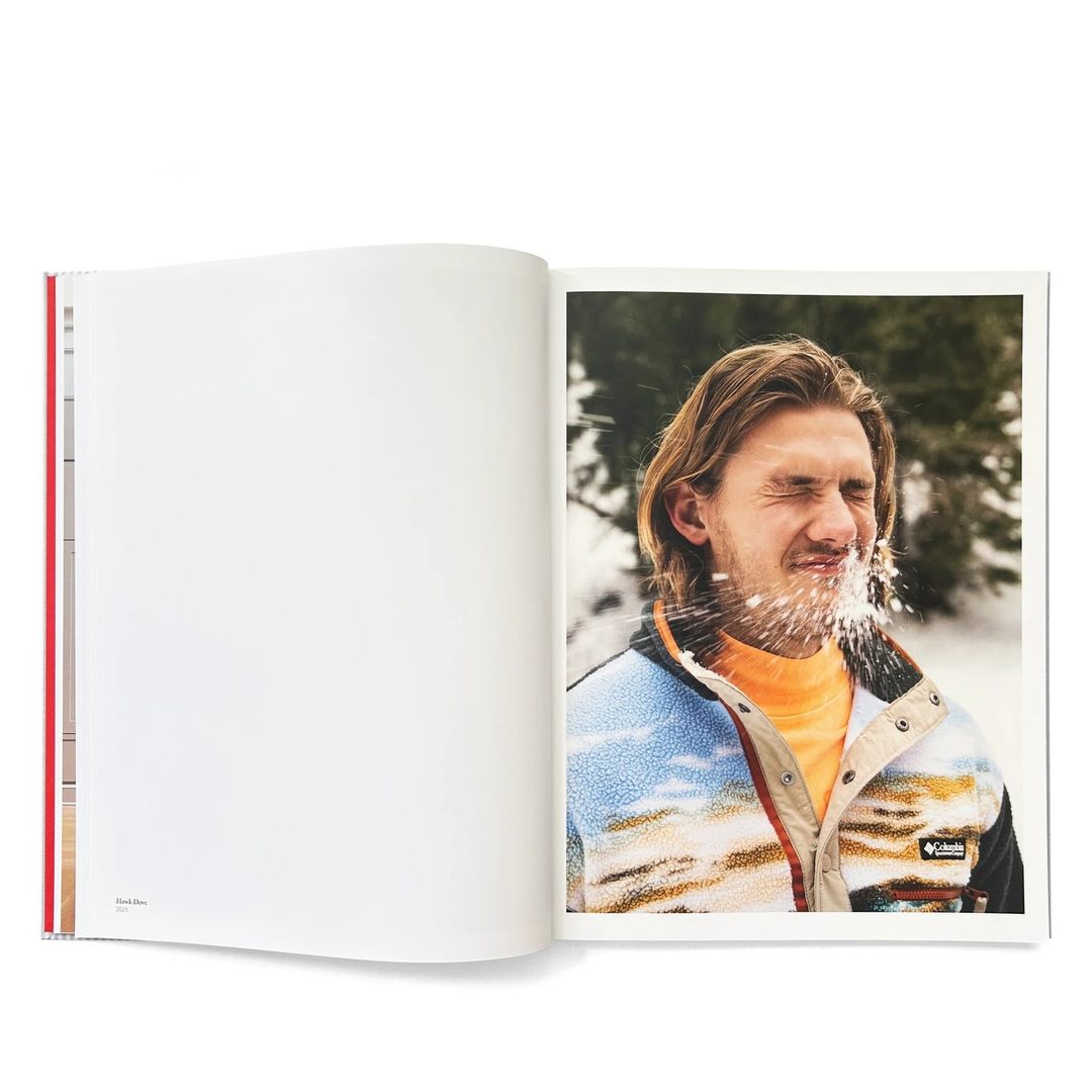 Image in an open book features a fair-skinned man outdoors with snow on his face, wearing a Columbia fleece jacket with a landscape pattern.