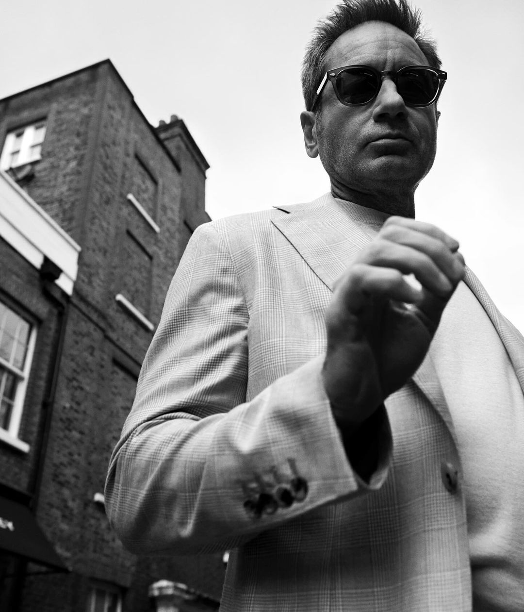 Monochrome portrait of a man in sunglasses and patterned blazer outdoors in London by Buzz White