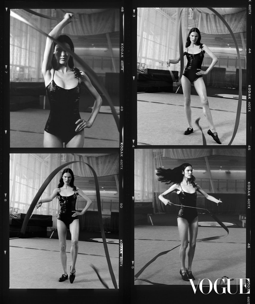 A young woman is captured in a black-and-white artistic photo performing rhythmic gymnastics with a ribbon in a minimalist studio setting.