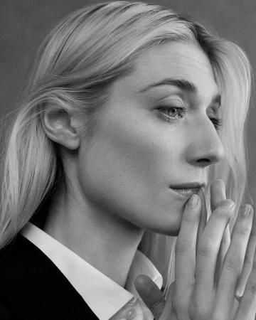 Close-up monochrome portrait of a woman holding her hands to her lips, wearing a white collared shirt.