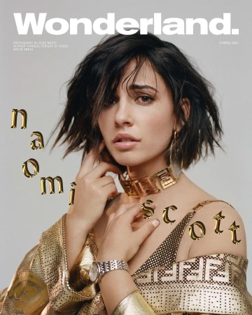 Naomi Scott on Wonderland Magazine cover with gold statement jewelry and graphic-patterned top, shot in a bright photo studio.
