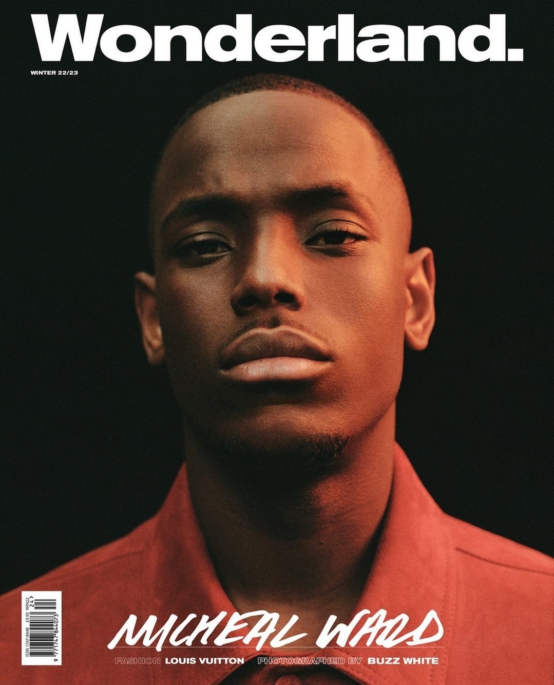 Wonderland magazine cover featuring Micheal Ward, winter 2022/23 issue. Portrait shot of an adult man in a red button-down shirt against a dark background.