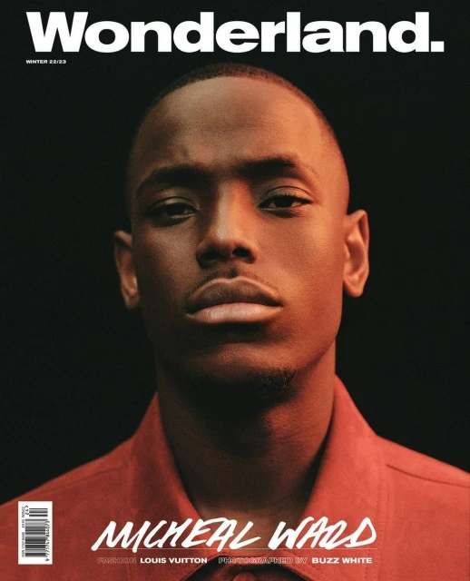 Wonderland magazine cover featuring Micheal Ward, winter 2022/23 issue. Portrait shot of an adult man in a red button-down shirt against a dark background.