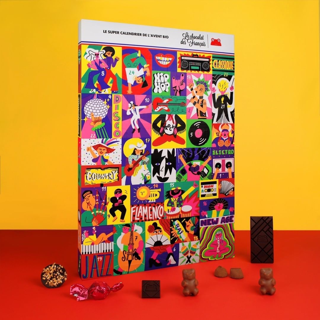 Advent calendar box with chocolate candies on red surface against yellow background. The box has different music styles illustrations.