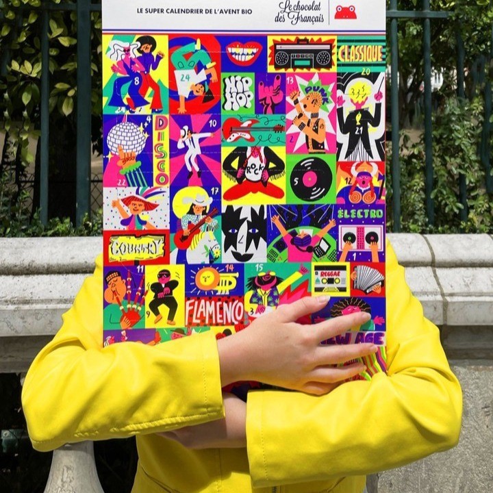 Person in yellow jacket holds advent calendar with musical themes against a park background, featuring pop art and colorful illustrations.