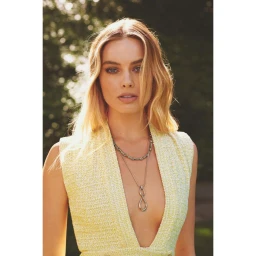 Margot Robbie wearing a sleeveless yellow tweed dress and layered silver necklaces photographed in natural light by Caitlin Cronenberg.