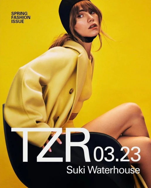 Magazine cover featuring Suki Waterhouse in a yellow coat and black beanie against a yellow background with bold white text.