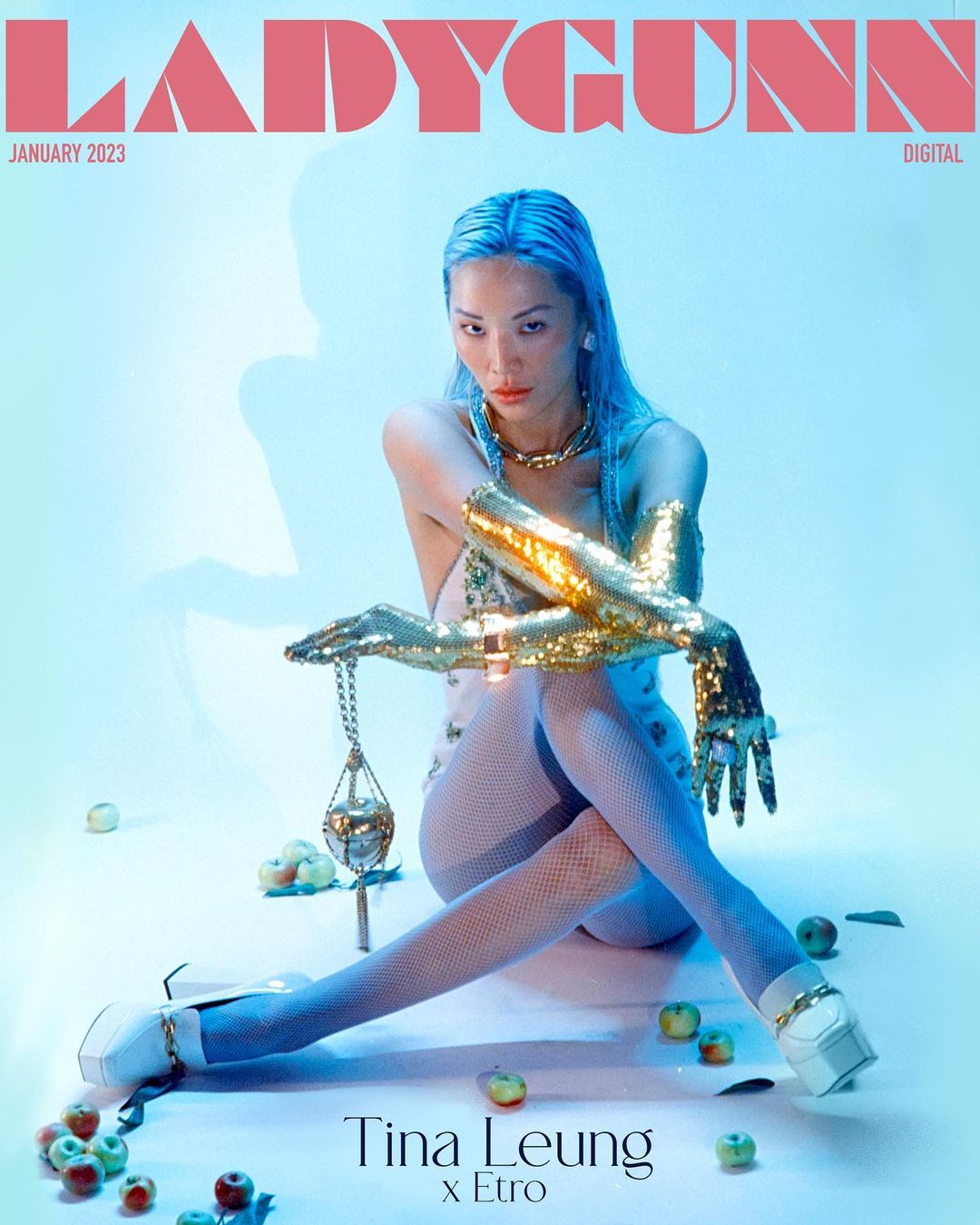 Ladygunn magazine cover featuring Tina Leung wearing shimmering gold sleeves and sitting amid green apples in a photo studio.