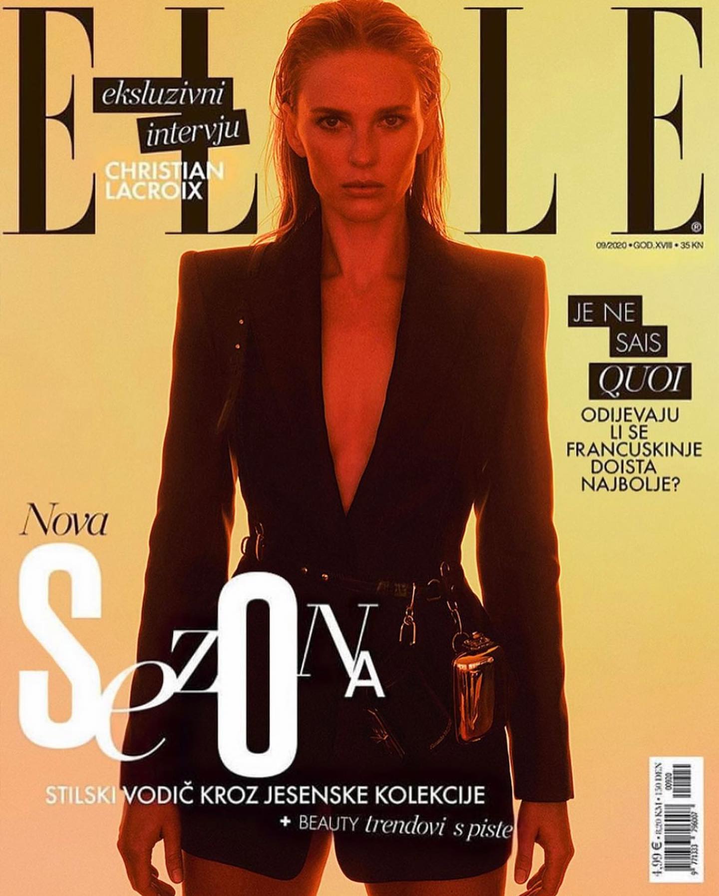 Elle magazine cover featuring a female model in a black blazer with a belt and attached metallic object. The background is a gradient yellow tone.