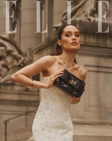 Elle Indonesia cover featuring a woman posing with a black purse, wearing a white dress, against a backdrop of a building.