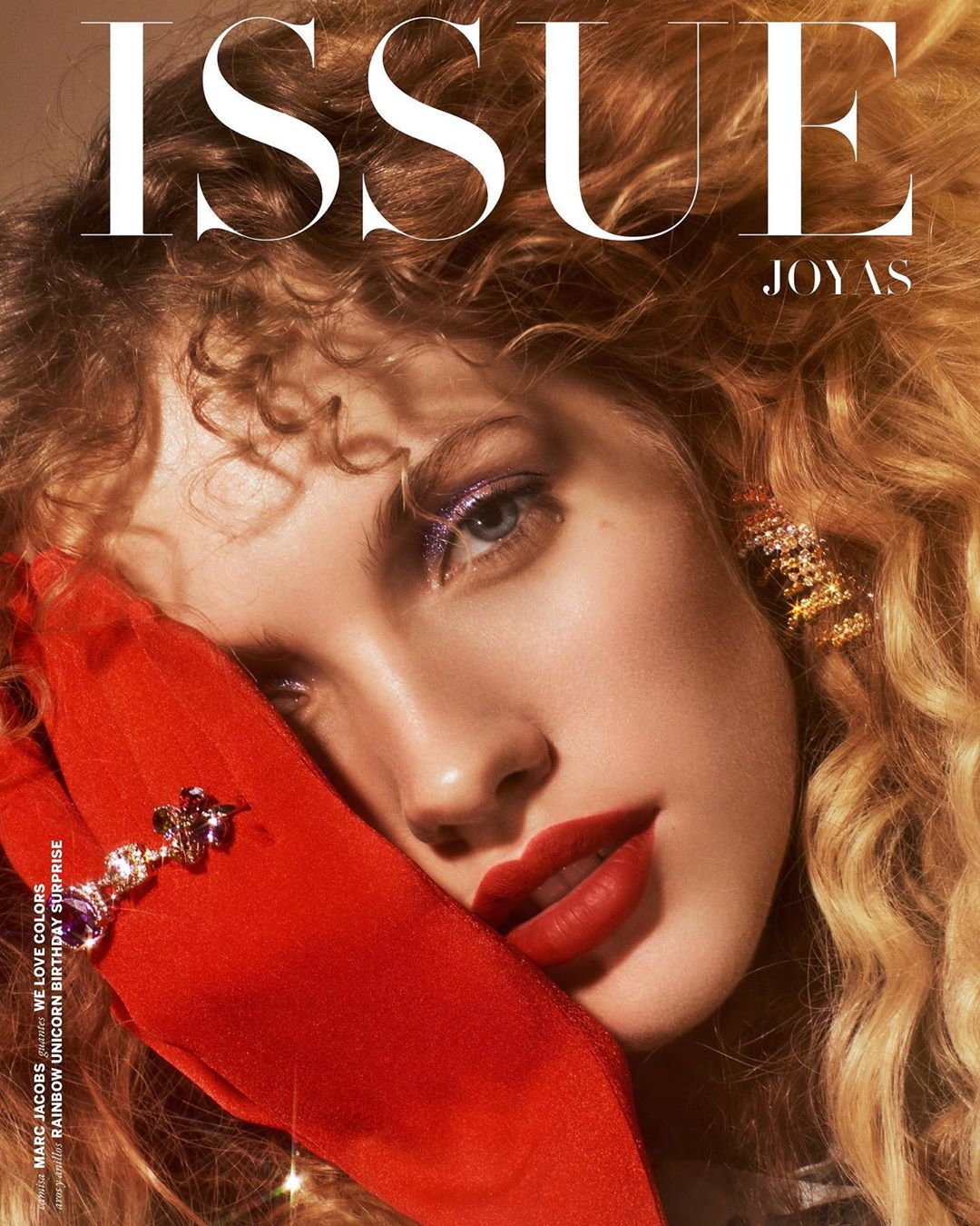 Magazine cover featuring a fair-skinned woman with curly hair, red lipstick, and jewelry, holding a red glove, with text overlay.