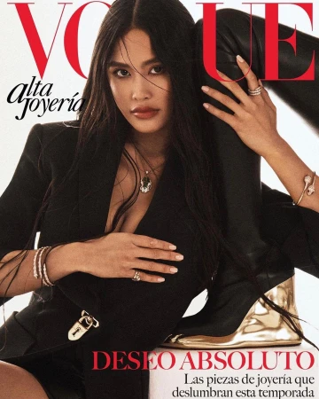 Woman in black blazer with gold lock detail and high leather boots posing for a magazine cover by Caleb and Gladys.