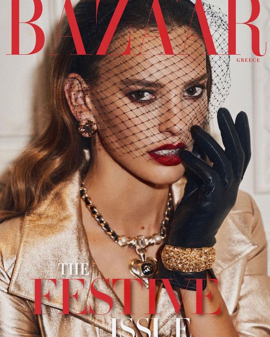 Bazaar Greece magazine cover features a woman in a gold jacket, dark gloves, and veiled headpiece with red lips. Dark red festive text.