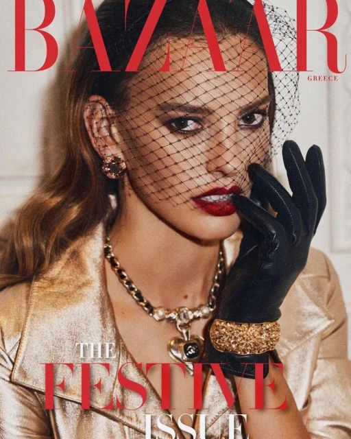 Bazaar Greece magazine cover features a woman in a gold jacket, dark gloves, and veiled headpiece with red lips. Dark red festive text.