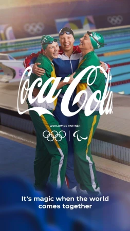 Three smiling athletes in swimwear and green tracksuits embrace beside a pool with a large Coca-Cola logo for a promotional sports image.