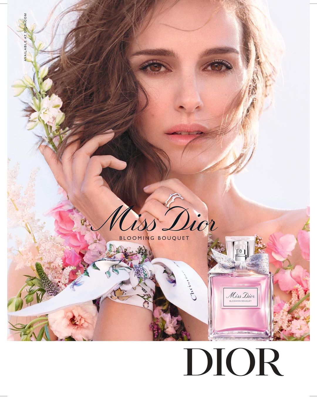 Natalie Portman stars in a Dior perfume ad, featuring a floral dress, a bouquet of flowers, and a bottle of Miss Dior Blooming Bouquet.