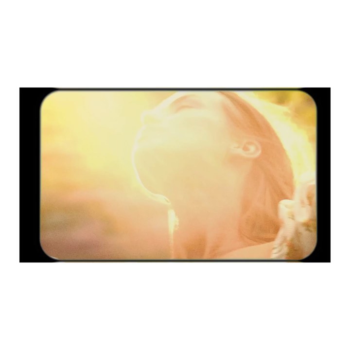 Adult woman with long hair tilts her head back as golden light shines on her face. The background is a soft golden yellow.