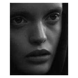 Close-up black and white portrait of a woman with dark hair framing her face shot by Camilla Akrans.
