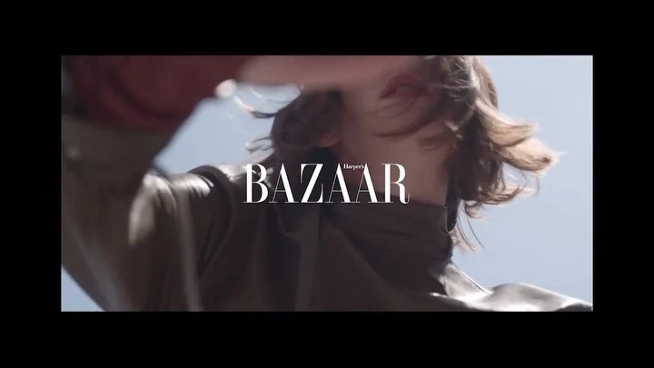 Fashion shot featuring an adult female model wearing a brown turtleneck sweater against a sky background, with Bazaar logo overlay.