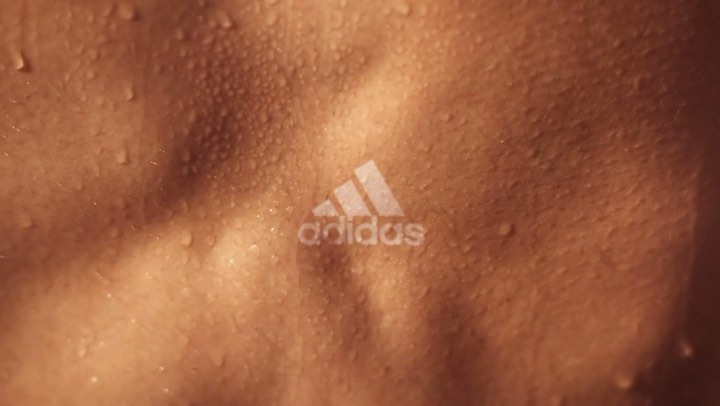 Close-up on a torso with water droplets and the Adidas logo, highlighting texture and athletic wear, suitable for sports and fitness themes.
