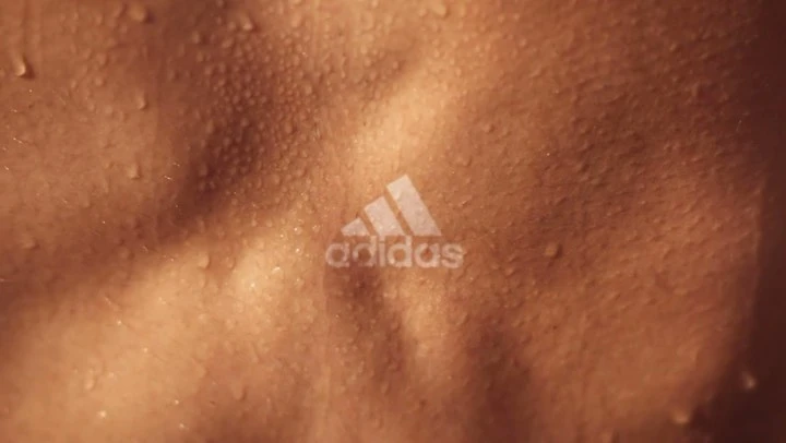 Close-up on a torso with water droplets and the Adidas logo, highlighting texture and athletic wear, suitable for sports and fitness themes.