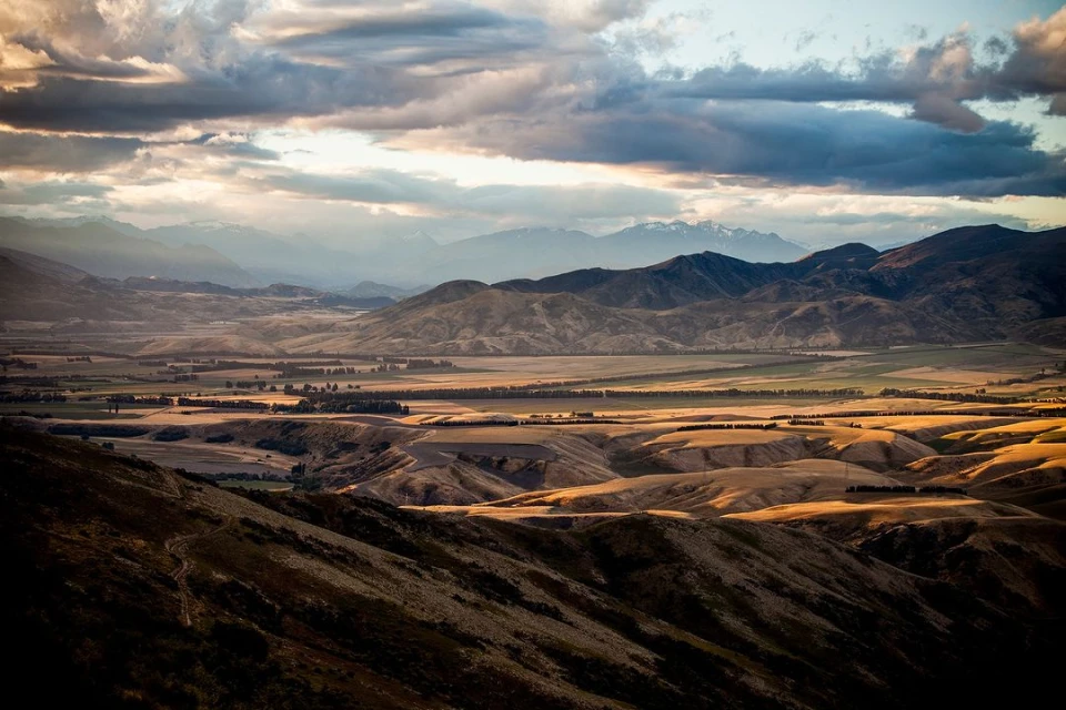 Panoramic view of a mountainous landscape with rolling hills under a cloudy sky, showcasing natural beauty and the vastness of the terrain.