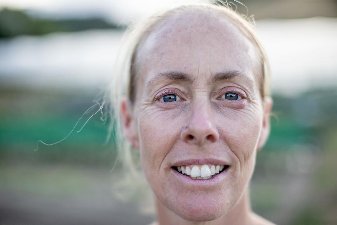 Close-up portrait of a smiling woman with light hair and blue eyes photographed outdoors in Auckland by Camilla Rutherford.
