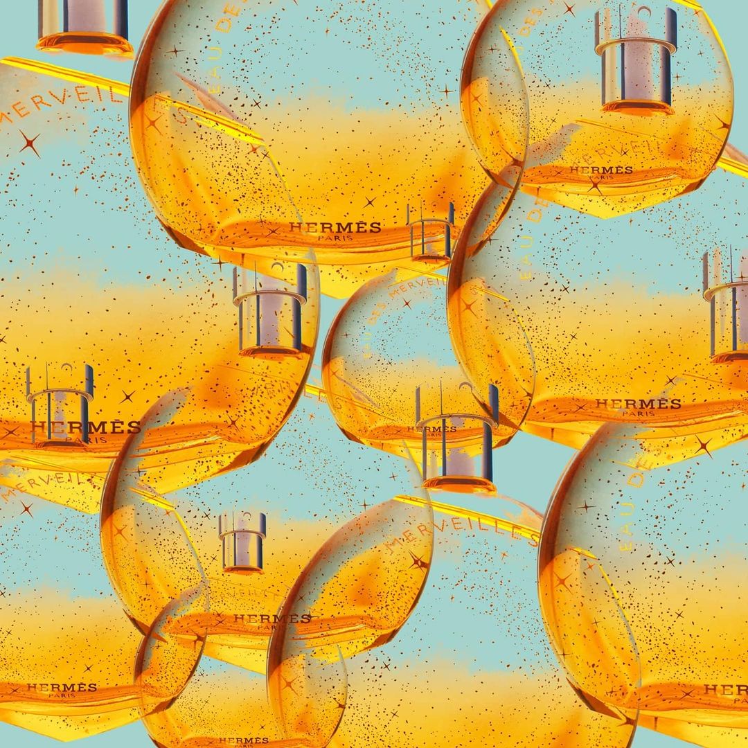 Multiple perfume bottles with golden liquid and silver tops are arranged against a light blue backdrop with gold sparkle accents.