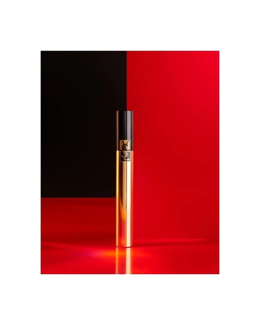 Close-up studio shot of a gold Yves Saint Laurent mascara tube against a red and black background, product photography for beauty.