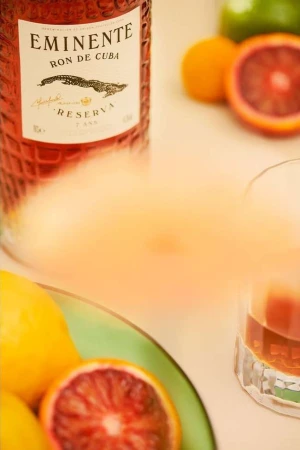 Eminente Ron de Cuba bottle with assorted citrus fruits on a light surface, capturing a vibrant and refreshing beverage scene.