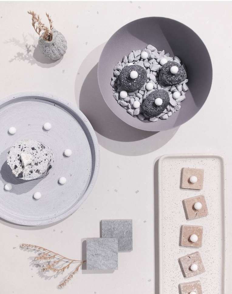Overhead shot of grey dessert food photography with stone-like design, small pebbles, and round white candy dots arranged on plates.