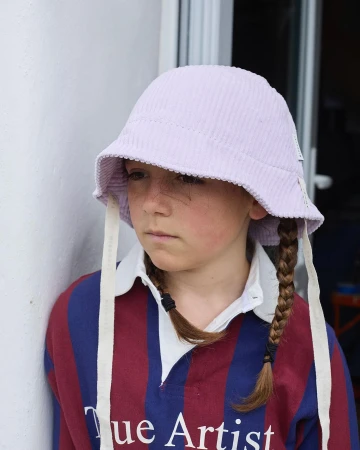 Young child wearing a light purple bucket hat and striped rugby shirt photographed by Camille Malissen in Paris