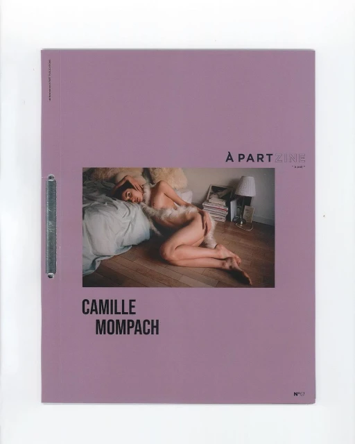 Art magazine cover featuring a reclining person on a bed with a lamp and books in the background, set against a lavender-colored background.