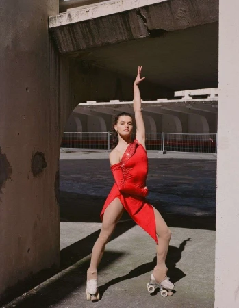 Dancer in a red dress on quad skates posing under a concrete bridge by Camille Mompach