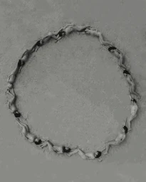 Aerial photograph of numerous people lying in a circle forming a ring shape on sandy ground.