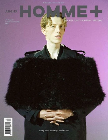 Arena Homme+ magazine cover features a male model in a black coat with faux fur stole against a lilac backdrop, showcasing fashion editorial.