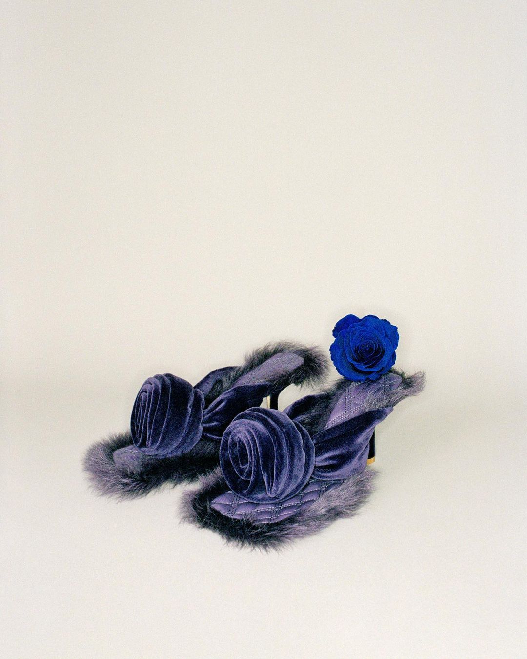 Pair of luxury blue velvet heeled sandals with fur trim and a blue rose accent, displayed against a plain white backdrop.