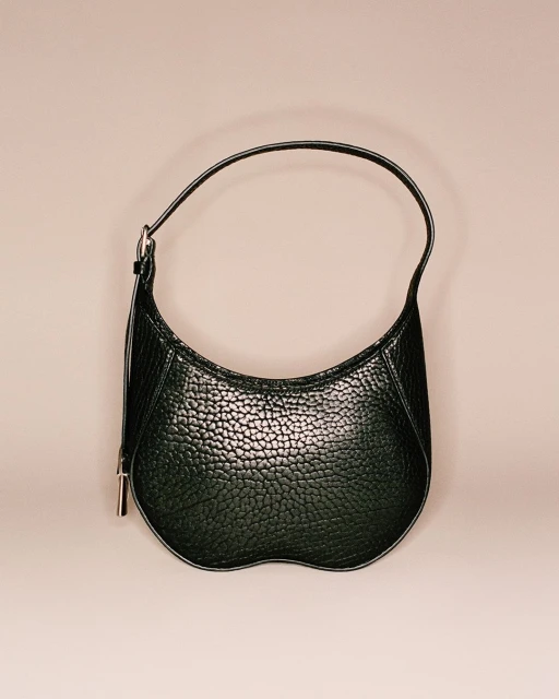 Stylish black pebbled leather handbag with a curved shape and a single handle, displayed against a soft, neutral background. Fashion accessory.