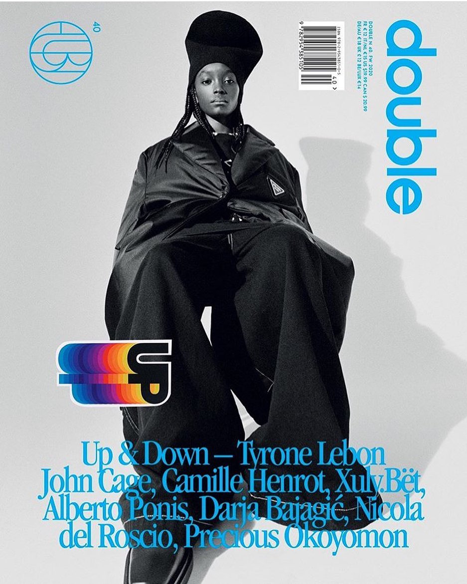 Magazine cover featuring a Black fashion model in an oversized black outfit. The cover includes the magazine's name, DOUBLE, in blue.