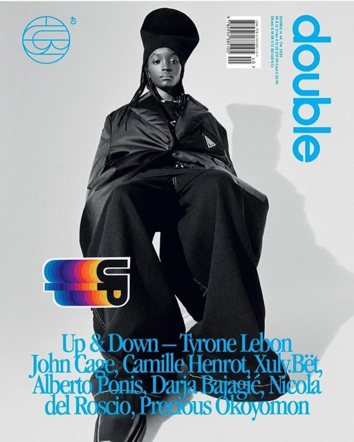 Magazine cover featuring a Black fashion model in an oversized black outfit. The cover includes the magazine's name, DOUBLE, in blue.