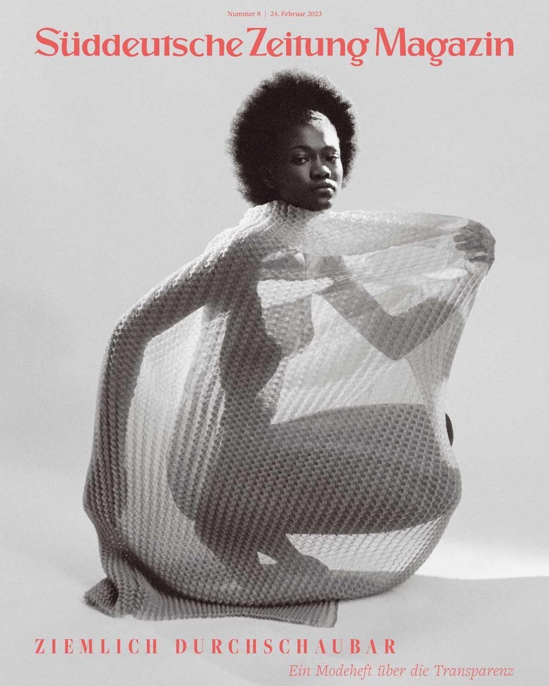 Magazine cover featuring an African American woman in a draped, mesh-like garment, against a neutral backdrop, with bold magazine text.