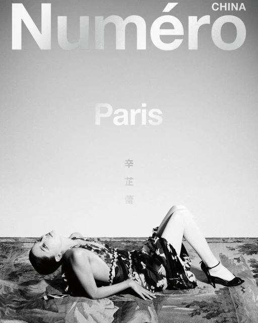 Fashion editorial featuring a supine woman in a dress and heels, lying on a patterned surface, against a gray gradient background with magazine text.