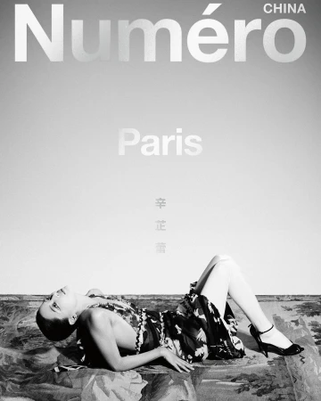 Fashion editorial featuring a supine woman in a dress and heels, lying on a patterned surface, against a gray gradient background with magazine text.