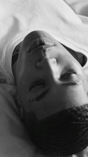 Close-up portrait of a Black man with short hair wearing a white t-shirt, captured in monochrome.