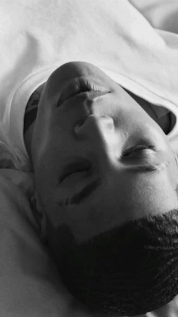 Close-up portrait of a Black man with short hair wearing a white t-shirt, captured in monochrome.
