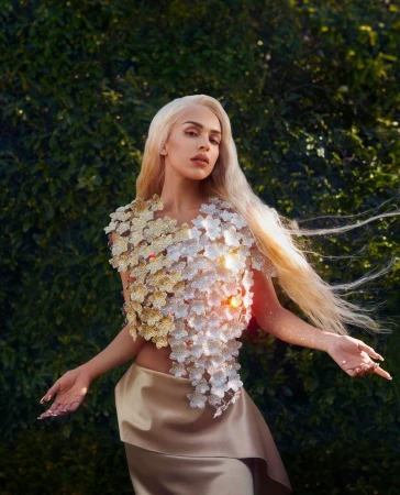 Woman with long platinum blonde hair wearing a floral embellished top and satin skirt outdoors in London